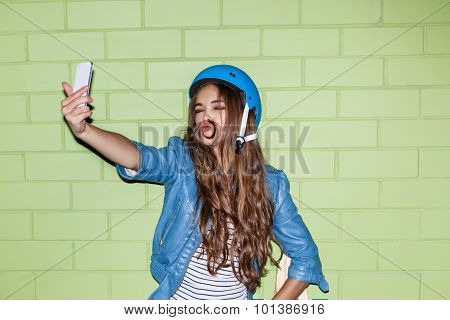 Beautiful Long-haired Woman With A Smartpnone Near A Green Brick Wall