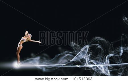 Hot young dancing woman in white bikini on dark background