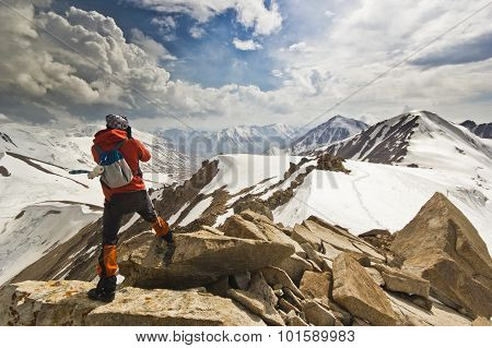 man standing on a cliff in mountains with poles