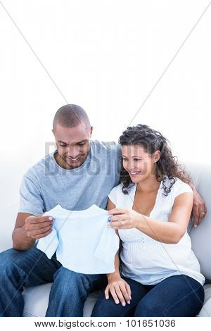 Happy couple looking at clothing on sofa in house