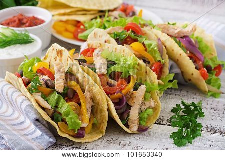 Mexican tacos with chicken, bell peppers, black beans and fresh vegetables.