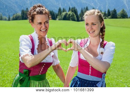 Two Women In Dirndl Forming A Heart With Her Hands