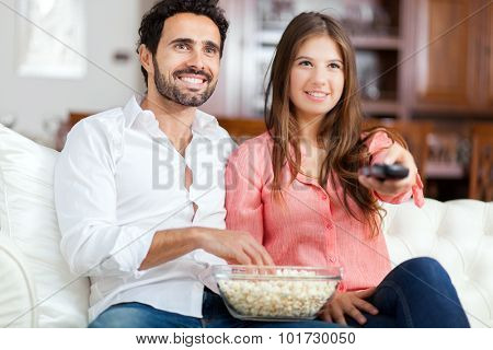 Young couple watching tv and eating pop-corn