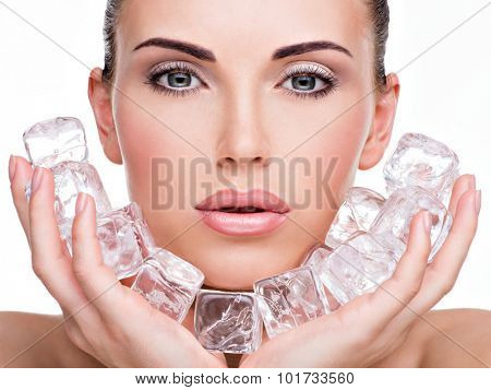 Beautiful young woman applies the ice to face. Skin care concept. 