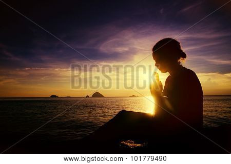 Young woman praying sunset over the Ocean Concept