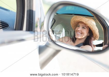 Reflection of happy woman in rearview mirror of car
