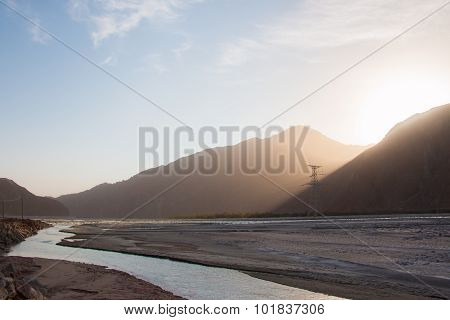 Sun Comes Out Behind Mountain Over A River Valley