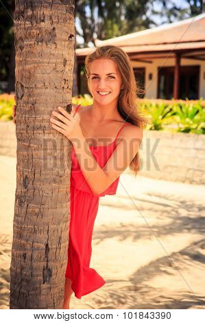 Blond Girl In Red Leans Out Of Palm Looks Into Camera