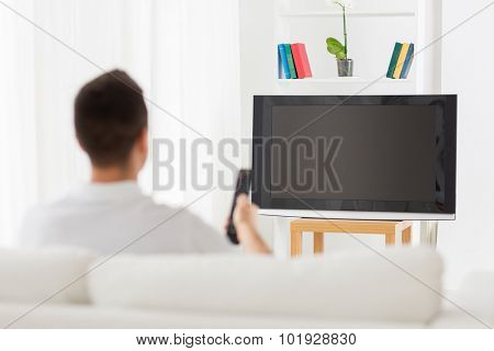 leisure, technology, mass media and people concept - man watching tv and changing channels at home from back