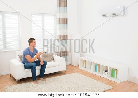 Young Man Operating Air Conditioner