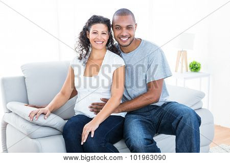 Portrait of couple sitting on sofa at home