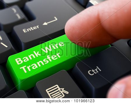 Pressing Green Button Bank Wire Transfer on Black Keyboard.