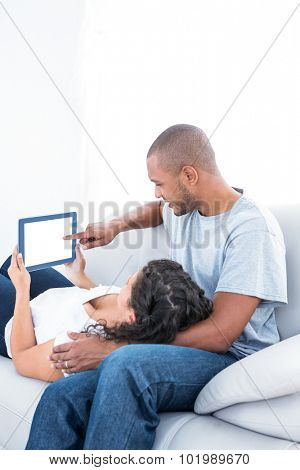 Young couple using tablet computer on sofa relaxing at home