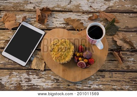 Overhead view of food with coffee cup on wooden tray by tablet computer at table