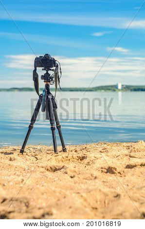 A camera on a tripod on the sandy seashore removes the seascape. Photographic equipment in the process of shooting the landscape. Camera while taking a photo or time-lapse