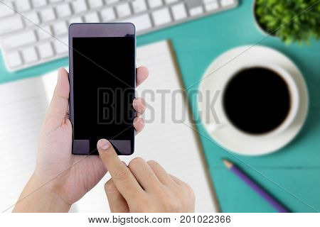 Man Hand Holding Smart Phone With White Blank Empty Screen On Blue Desk Table.