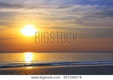 Beautiful blazing sunset landscape at sea and orange sky above it with awesome sun golden reflection on calm waves as a background. Amazing summer sunset view on the beach. Thailand
