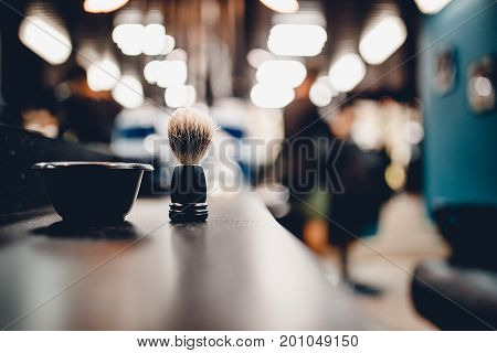 brush for shaving a beard along with a bowl, a blurred background of a hair salon for men, a barber shop