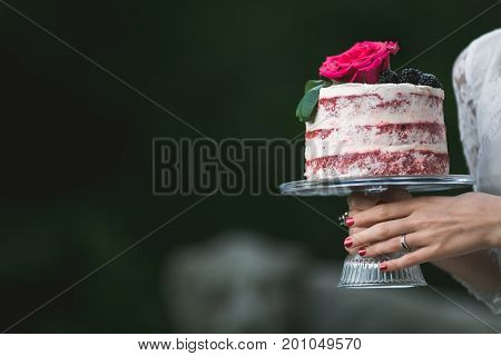 Anonymous woman in white dress holding platter with beautiful cake.