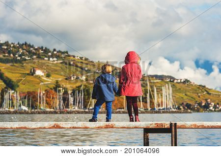 Two kids admiring amazing view of Lake Geneva Switzerland back view