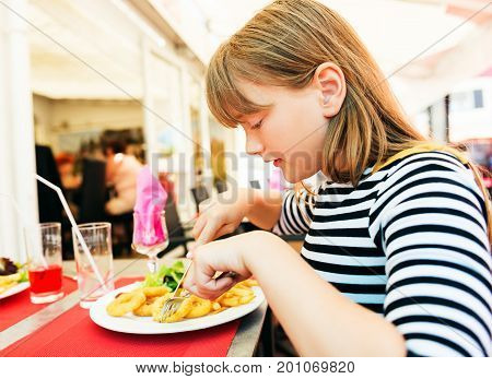 Child eating for lunch calamares a La Romana Fried Squid at restaurant table
