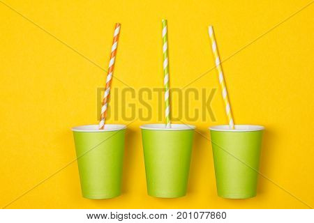 bundle of multi-colored drinking straws in a paper Cup on a yellow background. fashion minimal. flat lay