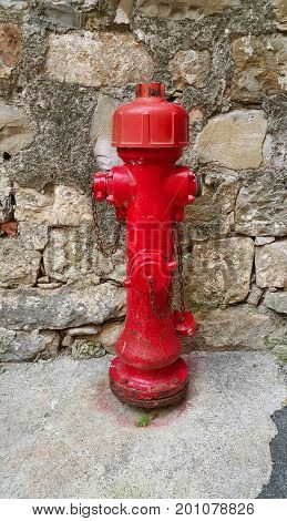 Red old fireplug against a stone wall background