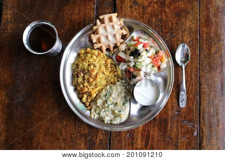 A full vegetarian dinner in metal dishes on a wooden table. View from above.