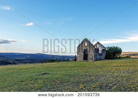 Rural old abandoned derelect farm building on dry winter landscape against blue cloudy sky in Lake Eland Game reserve in South Africa