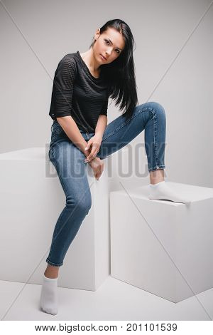 lifestyle, fashion and people concept: beautiful woman wearing casual clothes, posing on white background with big cube