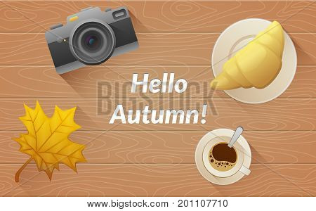 Hallo autumn text. Tasty buttery croissant and cup and camera of hot coffee on old wooden table with yellow leaves. Flat vector illustration