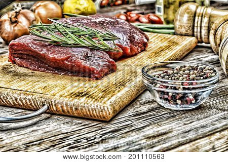 A piece of raw beef and rosemary on the kitchen table