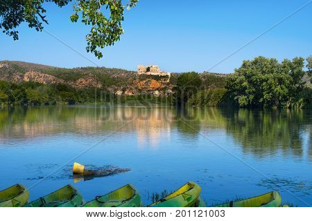 some kayaks at the Ebro River passing through Miravet, Spain, highlighting its Templar castle in the top of the hill