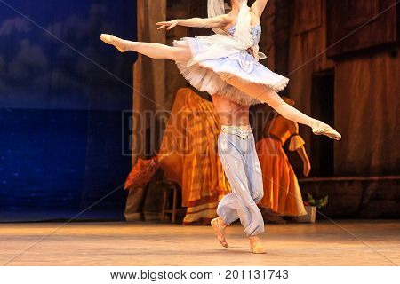 dance, perfection, ballet concept. slim ballerina in blue tutu with bright needlepoint, photographed in the movement, doing one of the most beautiful jump with help of her strong partner