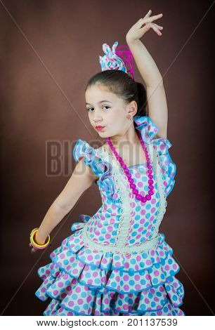 A sweet girl is dancing on a dark background. Spanish dance in a flamengo dress