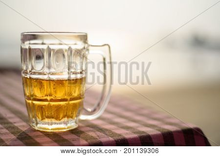 A glass of beer on a table on the background of the sea