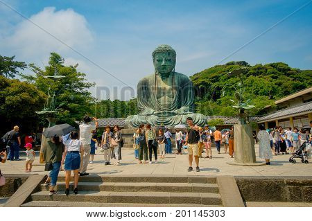 TOKYO, JAPAN JUNE 28 - 2017: Crowd of people posing and taking pictures at monumental bronze statue of the Great Buddha in Kamakura, Japan.