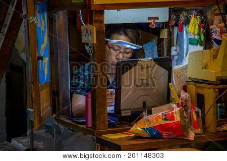 TOKYO, JAPAN JUNE 28 - 2017: Unidentified woman working in a coputer in the Fish Market Tsukiji wholesale in Tokyo Japan, Tsukiji Market is the biggest wholesale fish and seafood market in the world.