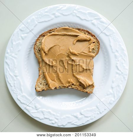 Peanut butter slathered on a slice of multi grain bread.