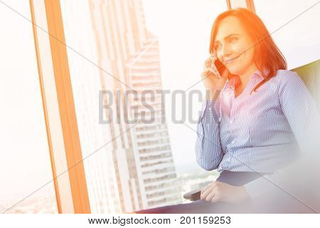Smiling businesswoman talking on cell phone in office