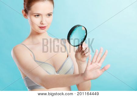 Woman Using Magnifying Glass To Examine Her Moles Skin