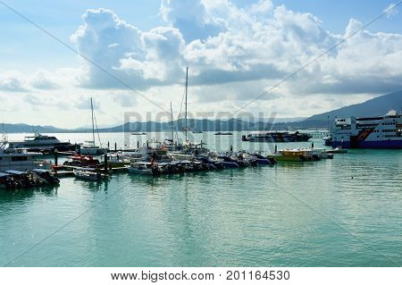Langkawi, Malaysia - 3rd May'17: Boats parked at a pier with blue water and blue cloudy sky. Various kinds of boats, Yachts and other vessels are parked at the Awana Porto Malai jetty