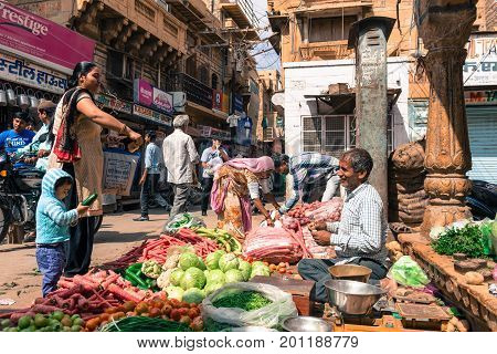 JAISALMER RAJASTHAN INDIA - MARCH 07 2016: Wide angle picture of indian men selling vegetables at the street market in Jaisalmer known as Golden City in India.