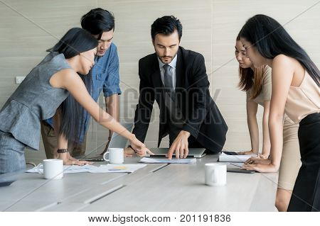 Group of multi-ethnic business partners discussing ideas in meeting room at office. Business people meeting corporate communication teamwork concept.