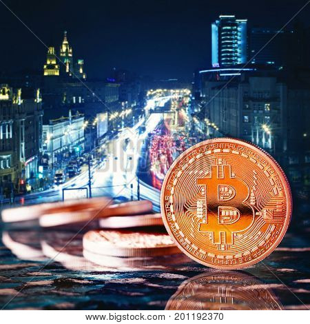 Photo Golden Bitcoins (new virtual money )close-up on a blue background.Coins against the background of the night city. Conceptual photo.