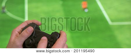 Hand holding game controller playing football game. Man Holding game controller joystick while playing console game.