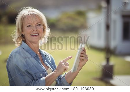 Portrait of smiling senior woman using digital tablet on a sunny day
