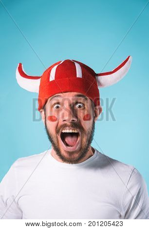 The football fan over blue. The young man looking at camera with different emotions on face