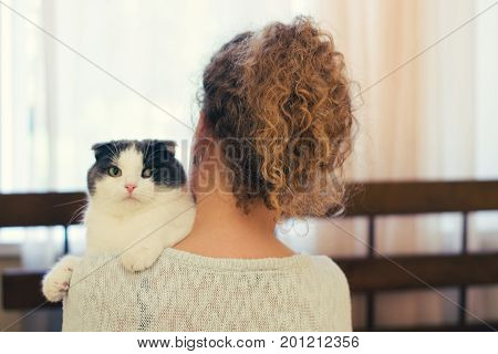 Girl holding a cat on her shoulder