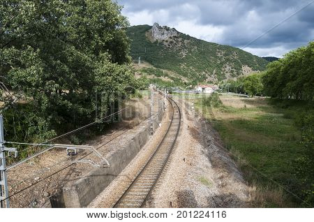 Iberian gauge railway track between Leon and Gijon on its way through La Pola de Gordon, Leon Province, Spain. In the background can be seen the town of Puente de Alba